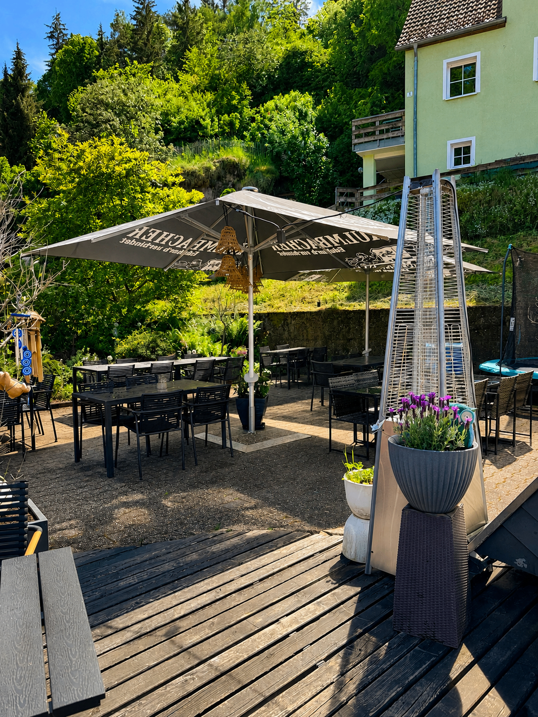 Biergarten des Restaurant Moena im Sonnenschein mit großem Sonnenschirm
