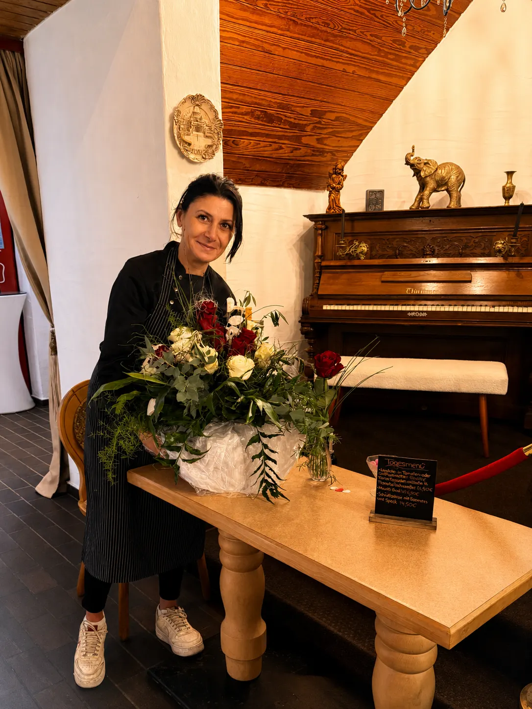 Gastgeberin mit Blumenstrauß am Klavier