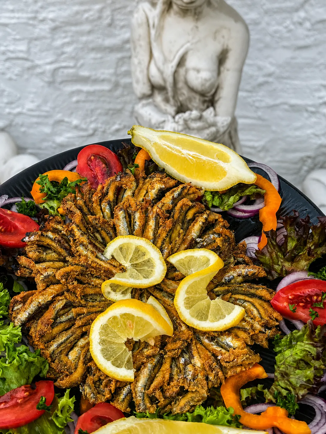 Gebratene Sardellen mit Zitronenspalten und Salatgarnitur